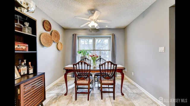 dining room featuring baseboards, a textured ceiling, and ceiling fan