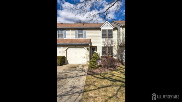 multi unit property featuring a garage and concrete driveway