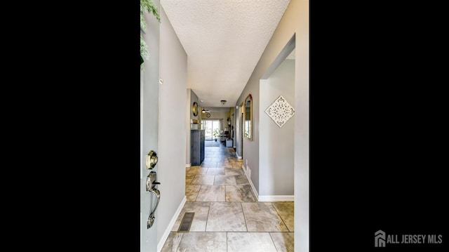 hallway with visible vents, baseboards, and a textured ceiling