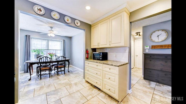 kitchen with light stone countertops, ceiling fan, black microwave, cream cabinets, and backsplash