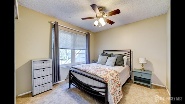 bedroom featuring light colored carpet, baseboards, and a textured ceiling