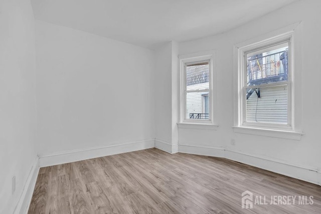 empty room with light wood-style flooring and baseboards