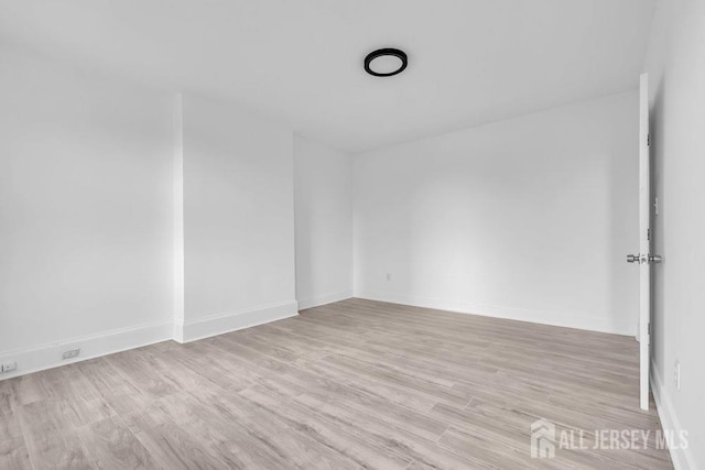 unfurnished room with light wood-style flooring and baseboards