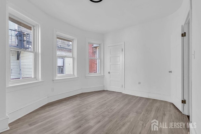 spare room featuring baseboards and wood finished floors