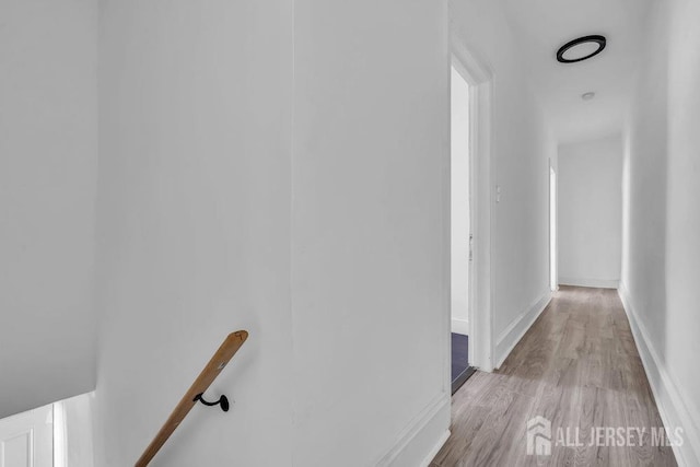 corridor with an upstairs landing, baseboards, and wood finished floors