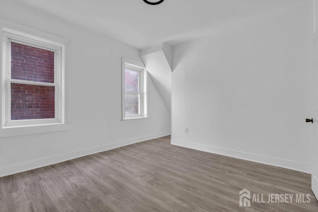 bonus room with baseboards and wood finished floors