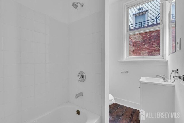 full bathroom featuring vanity, tiled shower / bath combo, and toilet