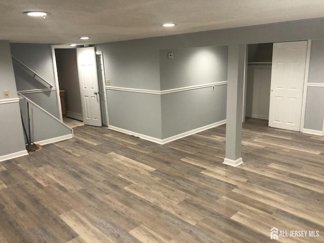 finished basement with recessed lighting, baseboards, baseboard heating, and wood finished floors