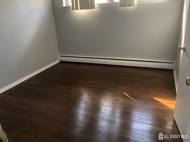 empty room with wood finished floors, baseboards, and a baseboard radiator