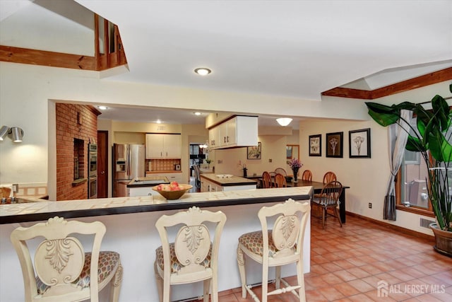 25 Deer Path, Holmdel, NJ 07733 - kitchen featuring stainless steel appliances, tile counters, a kitchen bar, and a peninsula