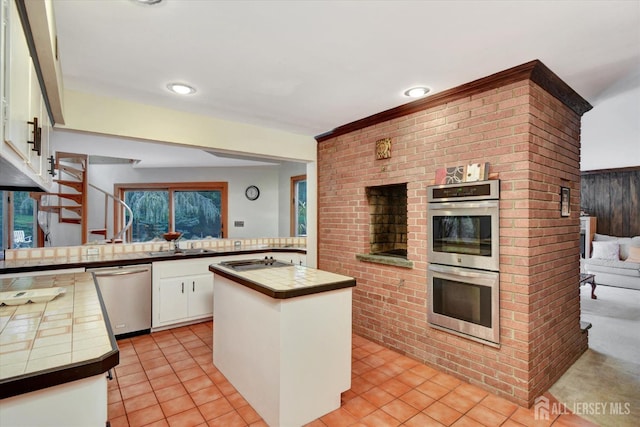 25 Deer Path, Holmdel, NJ 07733 - kitchen featuring appliances with stainless steel finishes, tile countertops, white cabinetry, a peninsula, and light tile patterned floors
