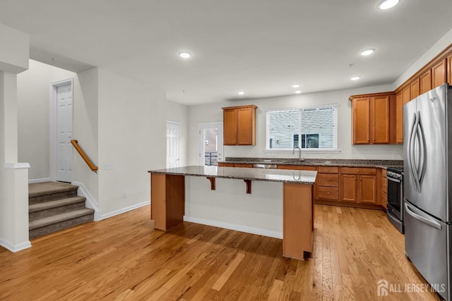 kitchen featuring light stone counters, appliances with stainless steel finishes, a center island, and light hardwood / wood-style floors