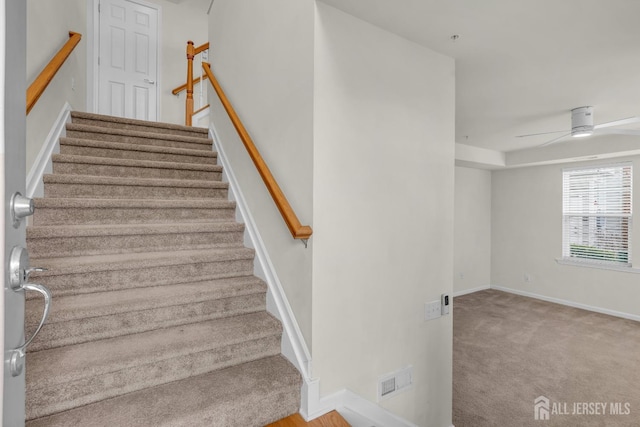 staircase with carpet floors and ceiling fan