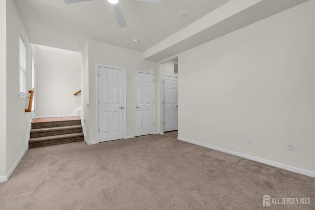 unfurnished bedroom with ceiling fan, light carpet, and two closets