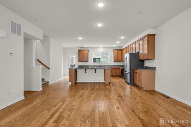 kitchen with a kitchen island, a breakfast bar, light wood-type flooring, and appliances with stainless steel finishes