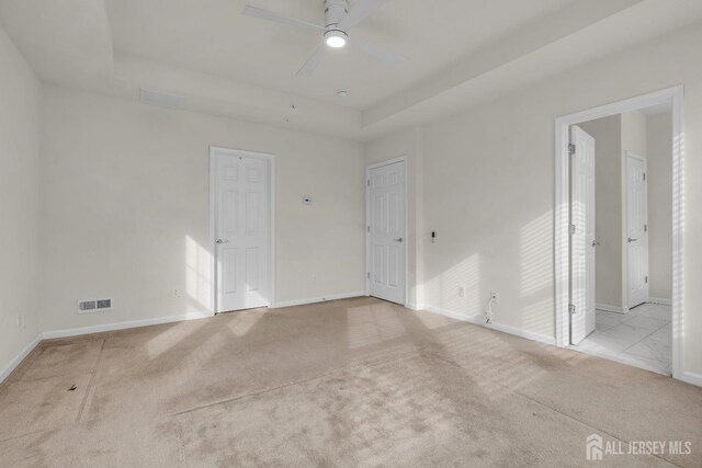 unfurnished room featuring light colored carpet, ceiling fan, and a tray ceiling