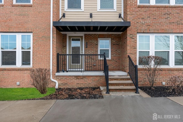 view of exterior entry featuring brick siding and crawl space