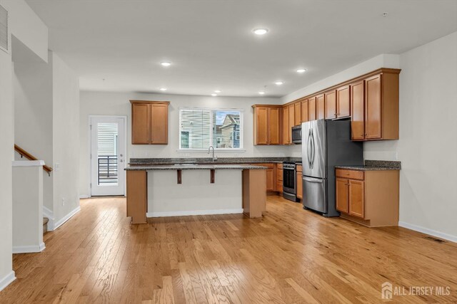 kitchen with sink, a breakfast bar area, a center island, light hardwood / wood-style flooring, and appliances with stainless steel finishes