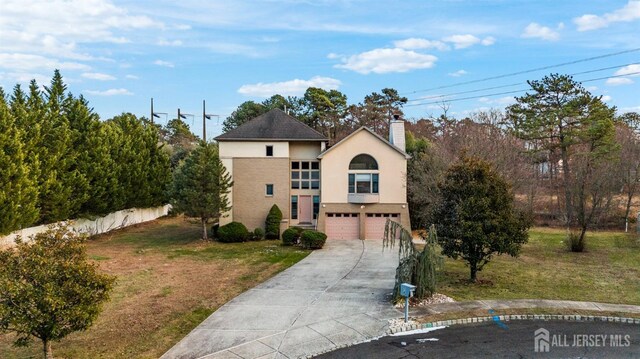 view of front of home with a garage, a front lawn, stucco siding, a chimney, and driveway