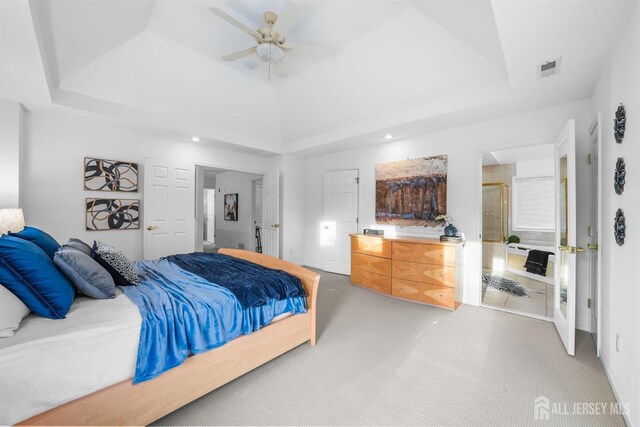 bedroom featuring light colored carpet, ceiling fan, a tray ceiling, and visible vents