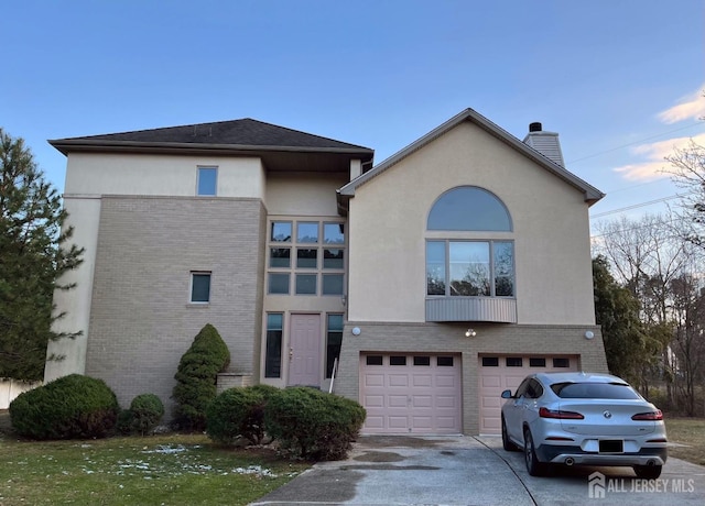 view of front of home featuring an attached garage, brick siding, driveway, stucco siding, and a chimney