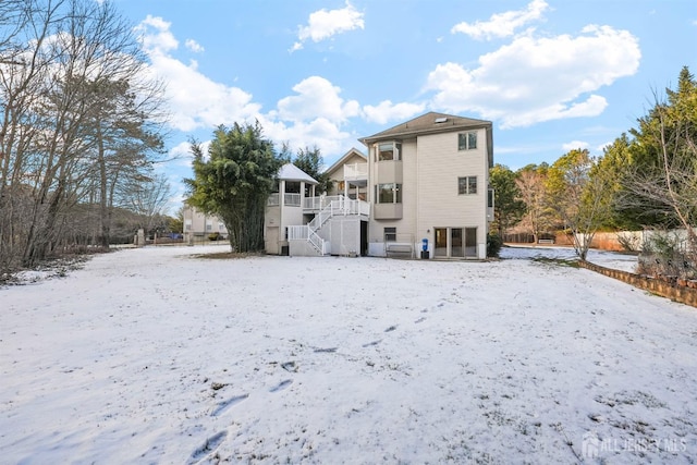 snow covered house featuring stairs