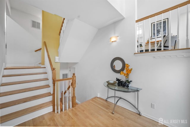 stairs with wood finished floors, visible vents, and baseboards