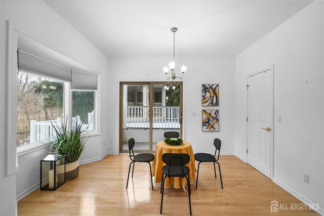 dining room with light wood-type flooring, an inviting chandelier, and baseboards