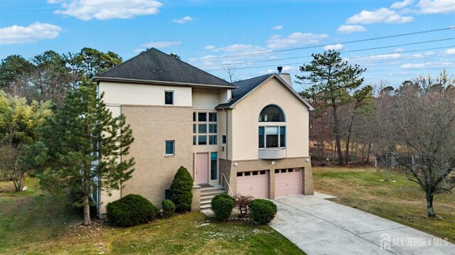 view of front of home featuring driveway, a chimney, a front lawn, an attached garage, and stucco siding