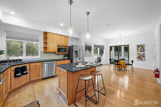 kitchen featuring light wood-style floors, a breakfast bar area, a center island, a sink, and appliances with stainless steel finishes