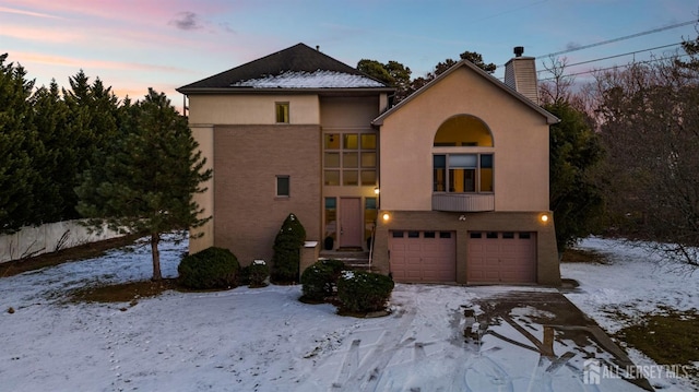 view of front of house with a chimney, an attached garage, and stucco siding