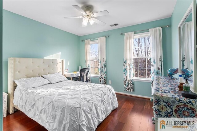bedroom with visible vents, baseboards, a ceiling fan, and wood finished floors