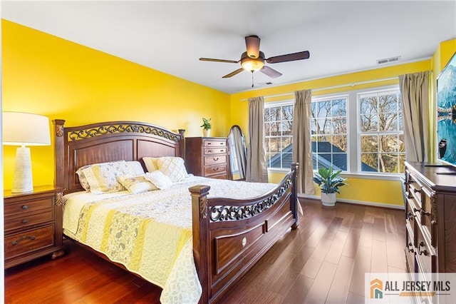 bedroom featuring dark wood-style flooring, visible vents, baseboards, and a ceiling fan