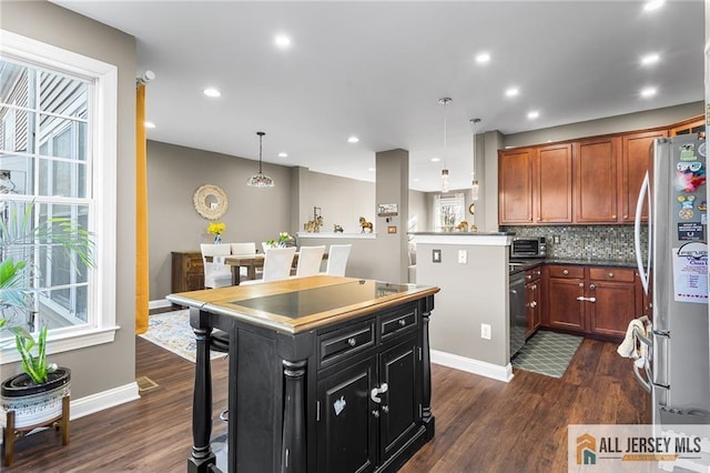 kitchen featuring decorative backsplash, freestanding refrigerator, dark wood-style floors, and brown cabinetry