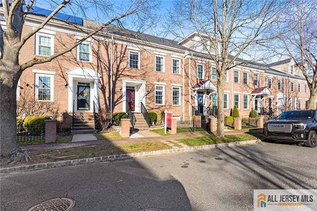 view of property featuring a fenced front yard, a residential view, and brick siding