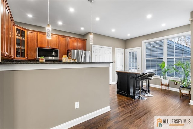 kitchen with glass insert cabinets, baseboards, appliances with stainless steel finishes, dark wood-style floors, and brown cabinets