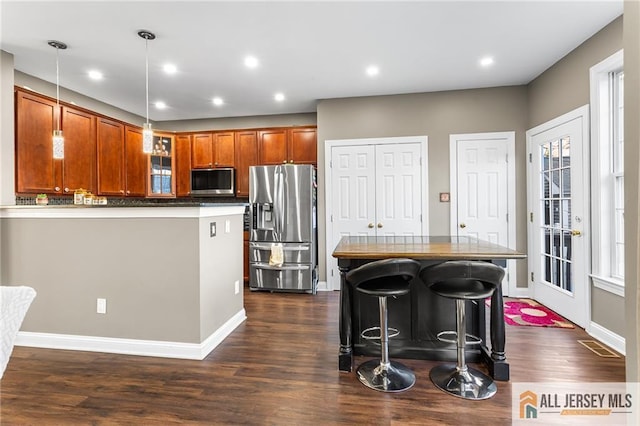 kitchen featuring glass insert cabinets, decorative light fixtures, appliances with stainless steel finishes, dark wood finished floors, and recessed lighting