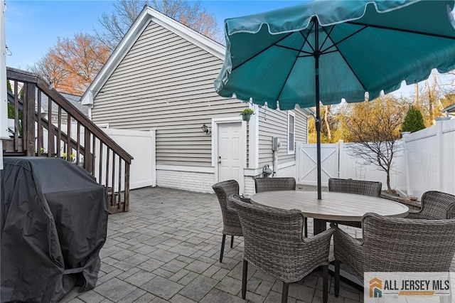 view of patio / terrace featuring a grill, a fenced backyard, outdoor dining area, and stairway