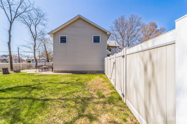 rear view of property with a lawn, a fenced backyard, and a patio area