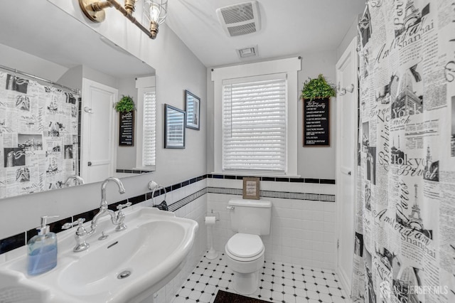 bathroom featuring visible vents, toilet, wainscoting, and a sink
