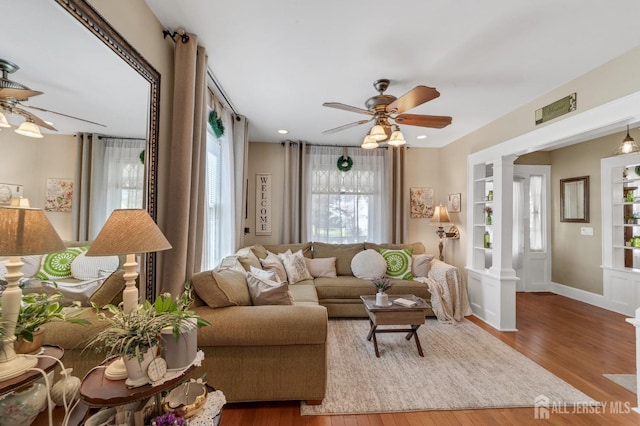 living room with ceiling fan, decorative columns, wood finished floors, and baseboards