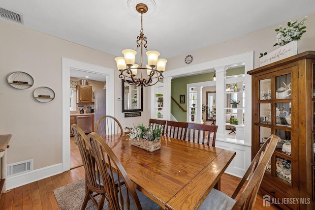 dining area featuring baseboards, visible vents, hardwood / wood-style flooring, and a notable chandelier