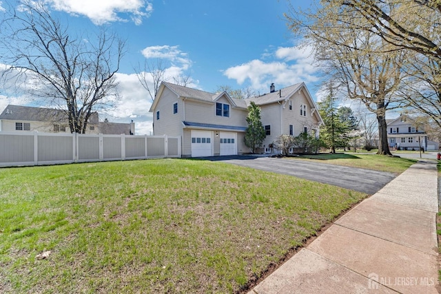 view of side of home with fence, a lawn, aphalt driveway, and an attached garage