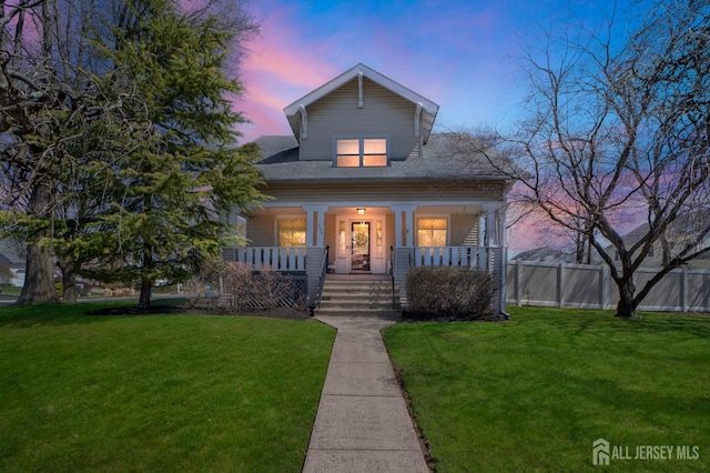 bungalow-style home with fence, a porch, and a yard