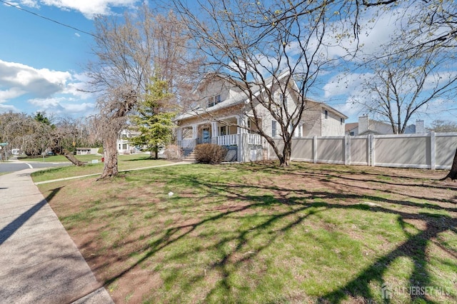 view of yard with covered porch and fence