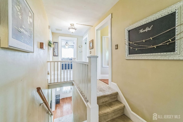 stairway featuring baseboards, visible vents, and wood finished floors