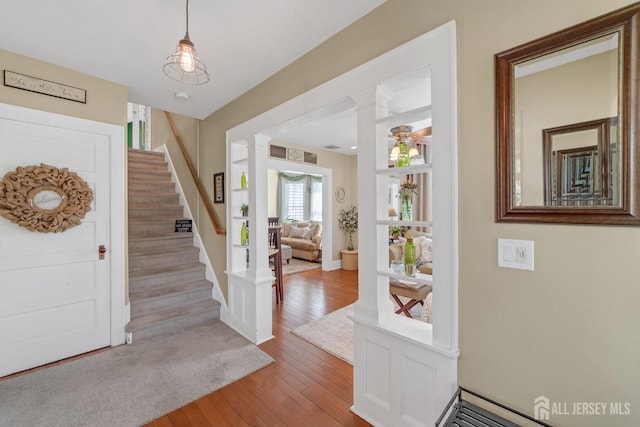 entrance foyer with ornate columns, stairway, a ceiling fan, and wood-type flooring
