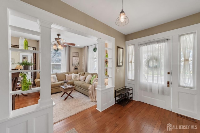 entrance foyer with light wood finished floors, visible vents, and decorative columns