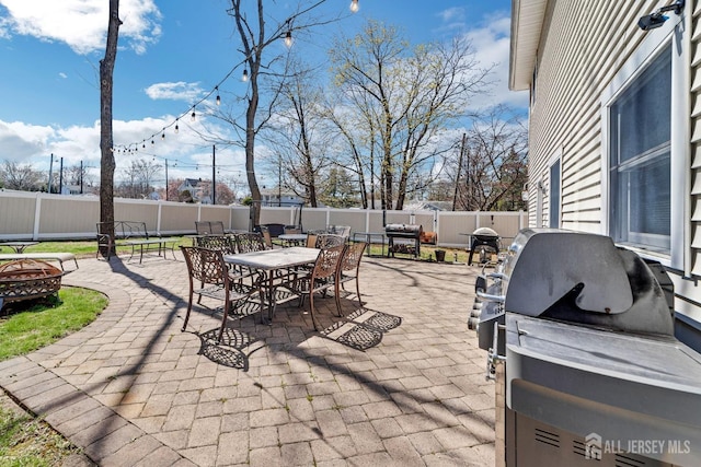 view of patio with outdoor dining space, a fire pit, area for grilling, and a fenced backyard
