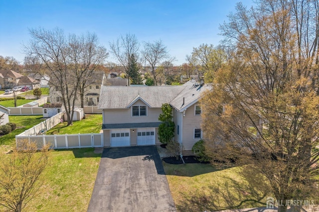 traditional home featuring a garage, fence, aphalt driveway, and a front lawn
